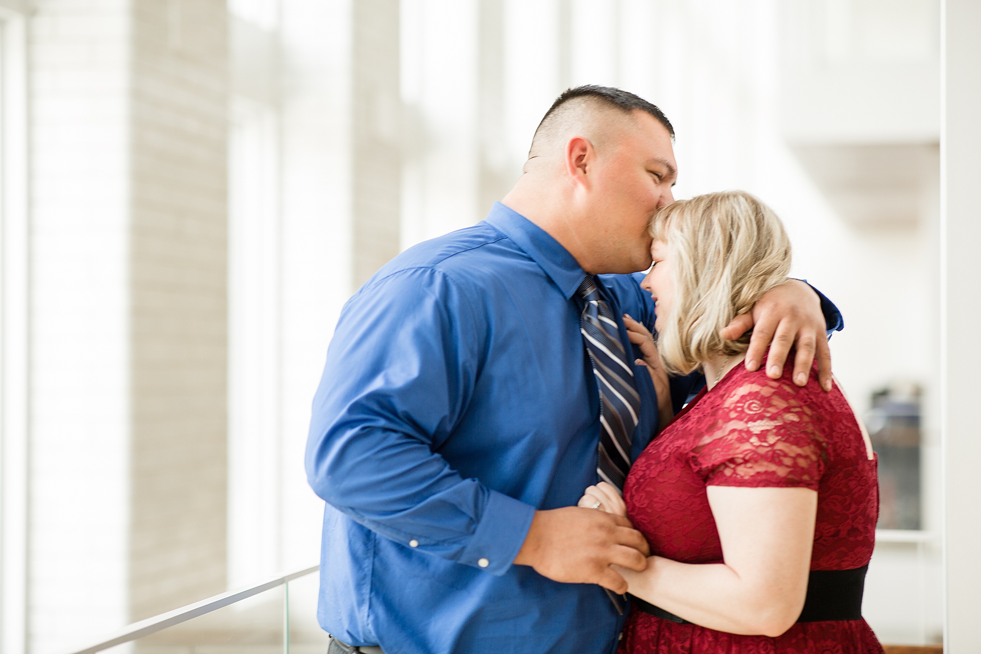 groom kisses bride's forehead during portraits inside Central Library