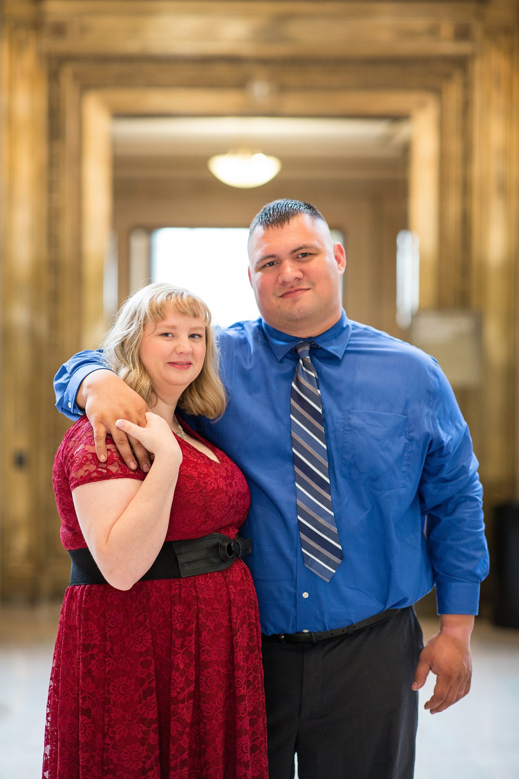 engaged couple poses in gold doorframe at Central Library