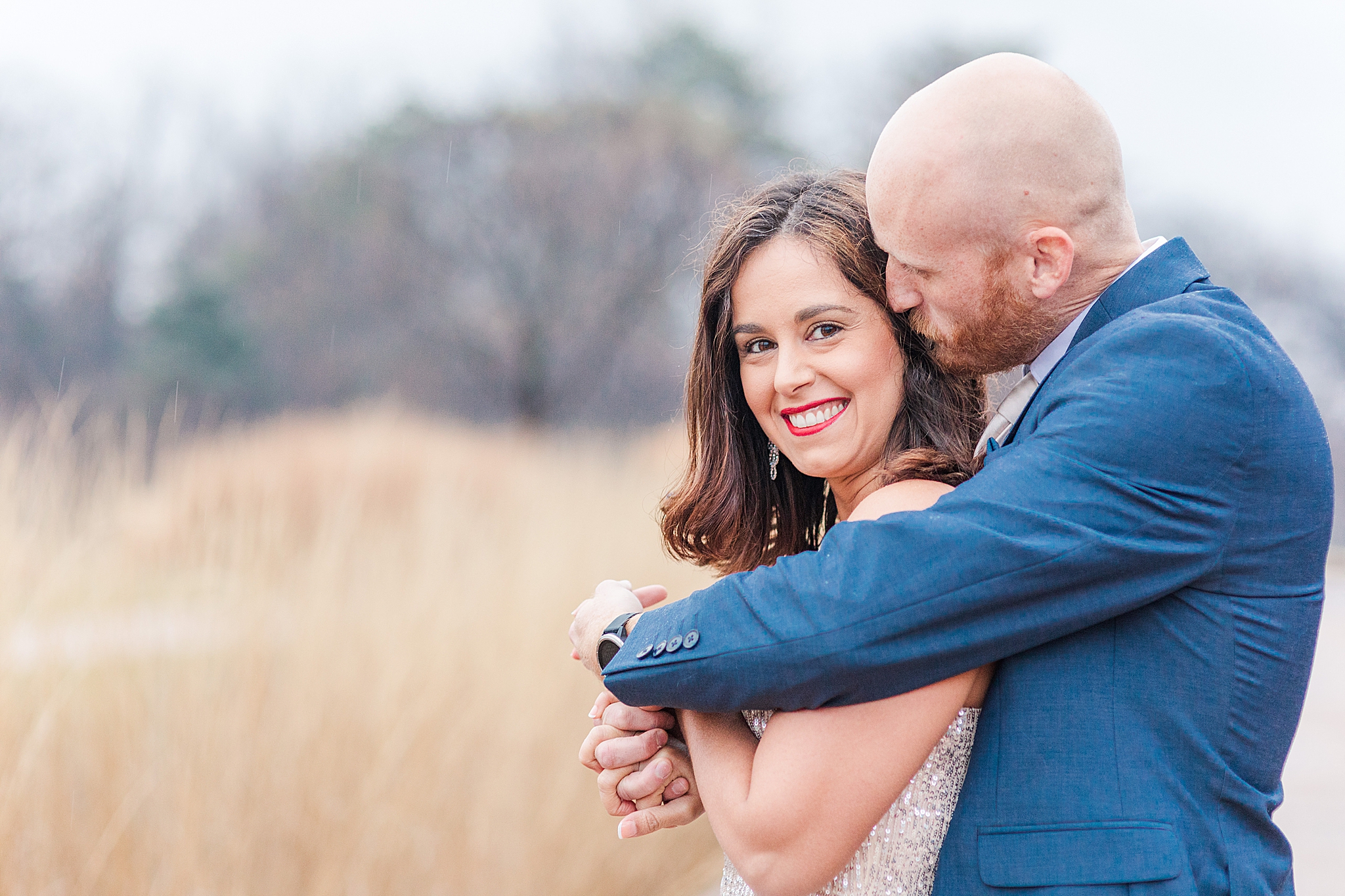 groom hugs bride from behind during winter engagement photos