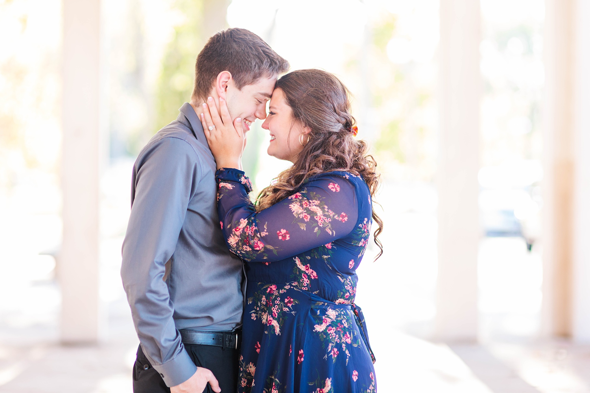 bride holds groom's cheeks during Forest Park engagement session