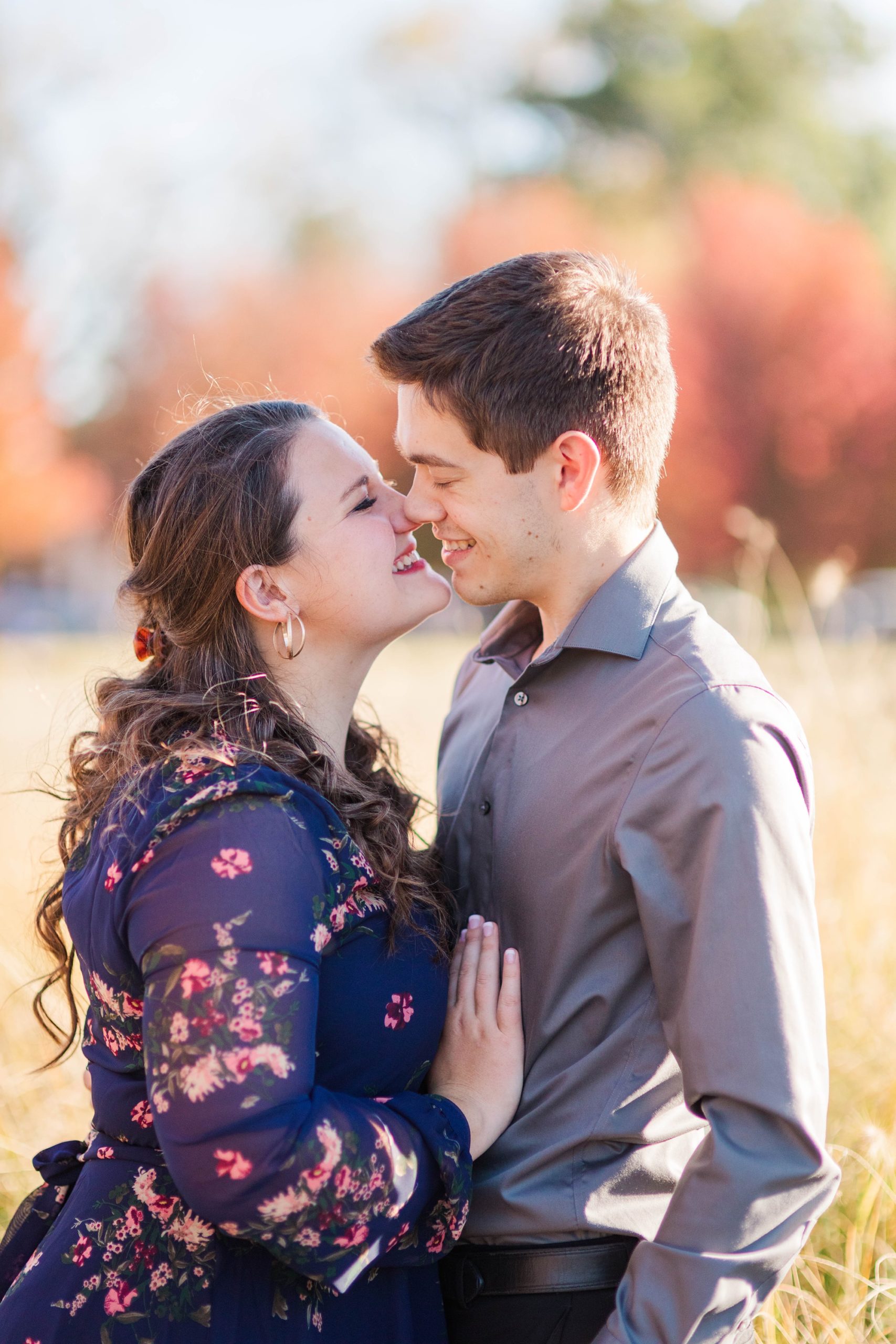 bride and groom stand nose to nose on edge of field during fall Forest Park engagement session