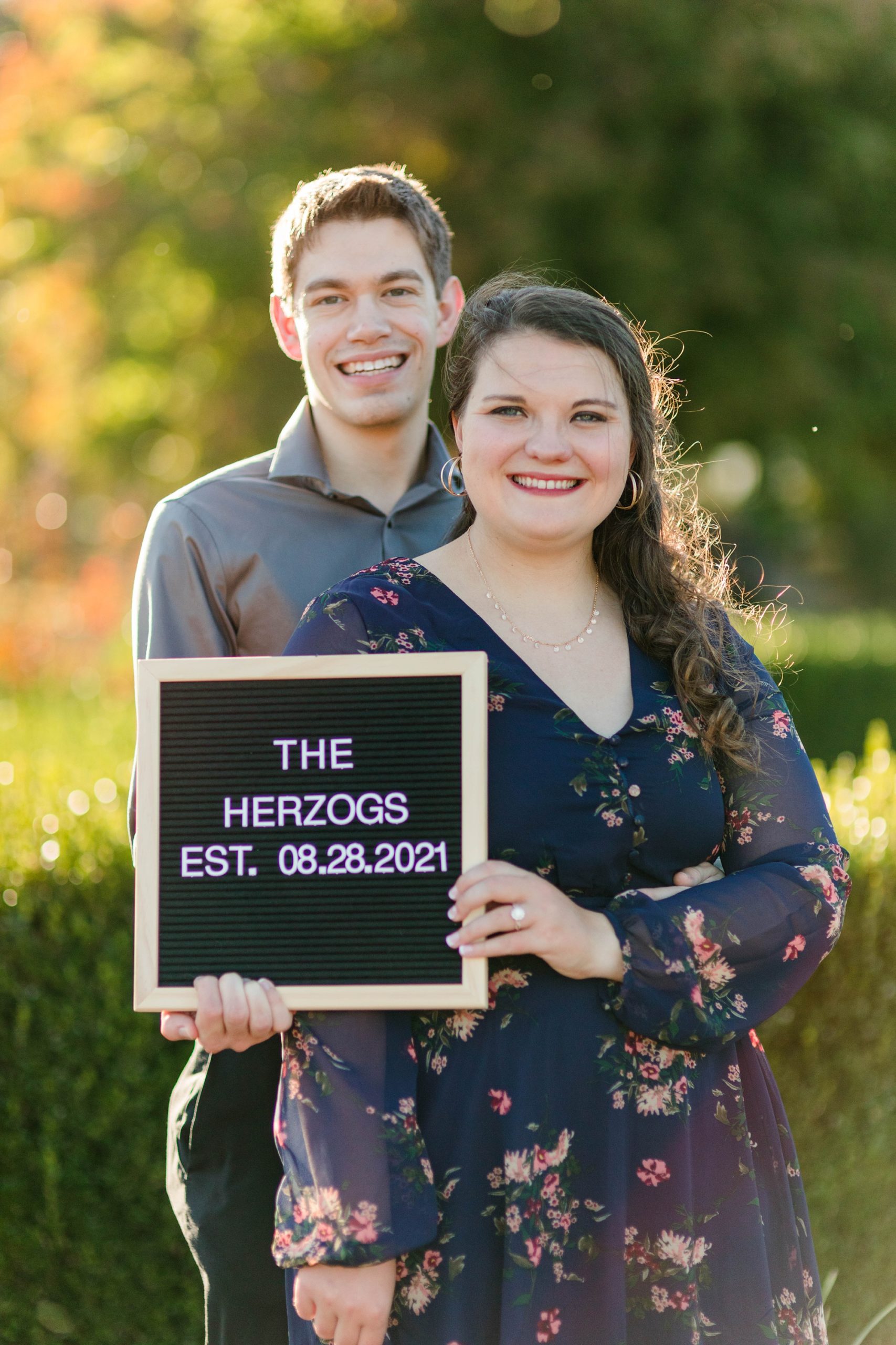 couple poses with letter board during fall Forest Park engagement session