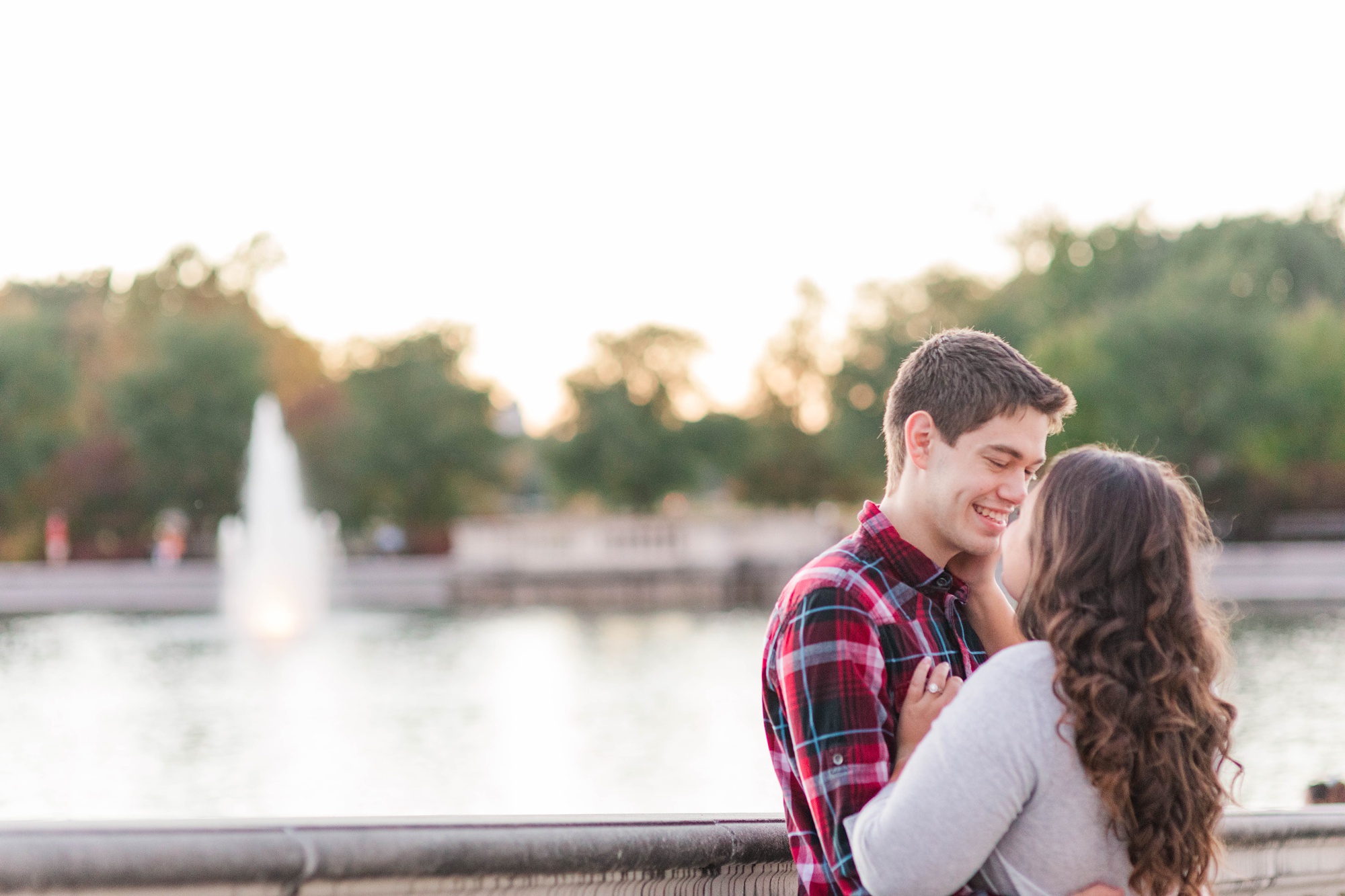 engaged couple poses by fountain in St. Louis park
