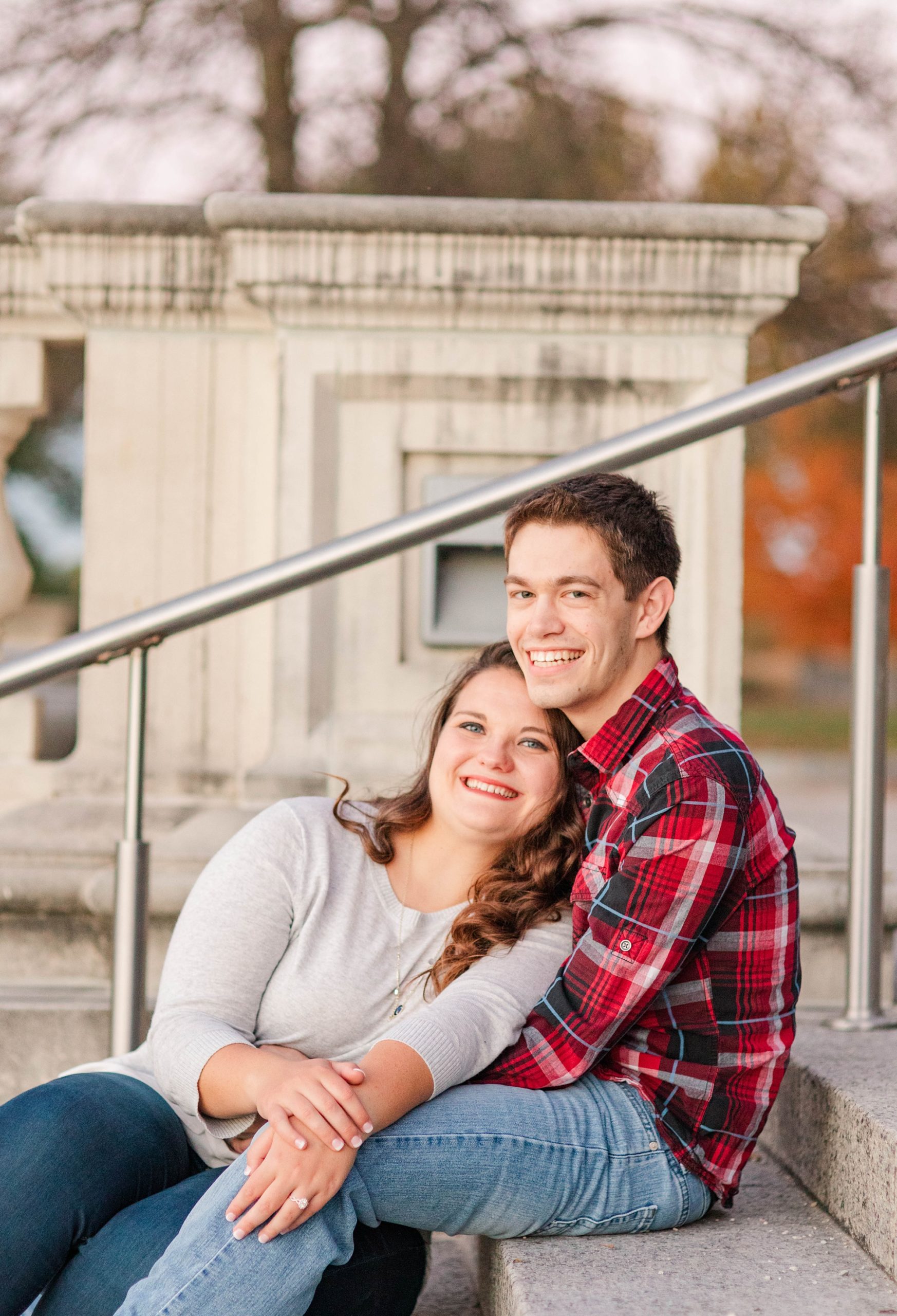 engaged couple sits on steps in St. Louis park