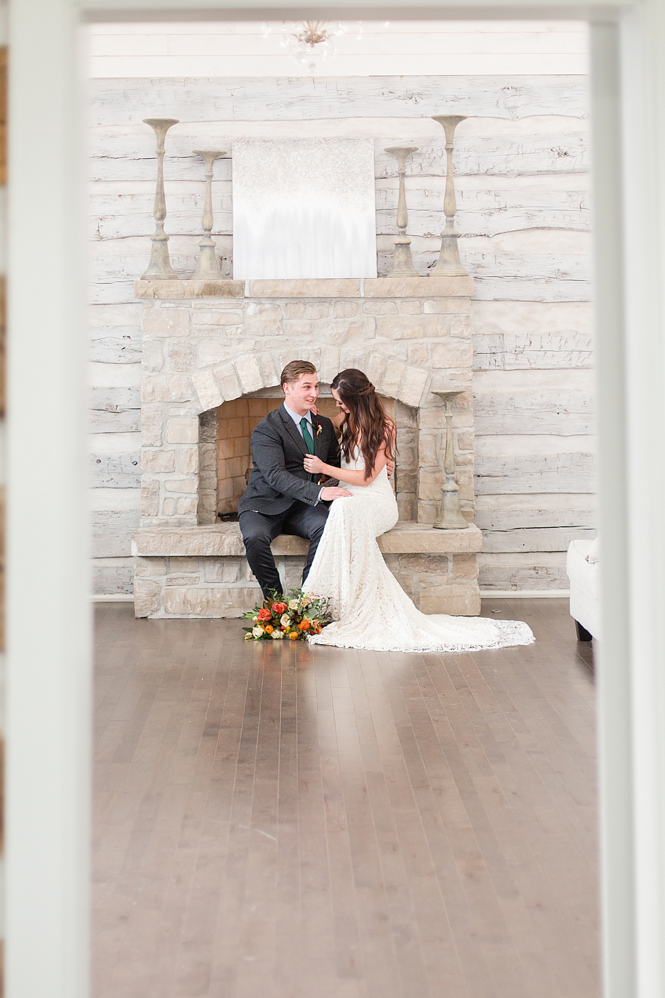 bride and groom sit on stone fireplace