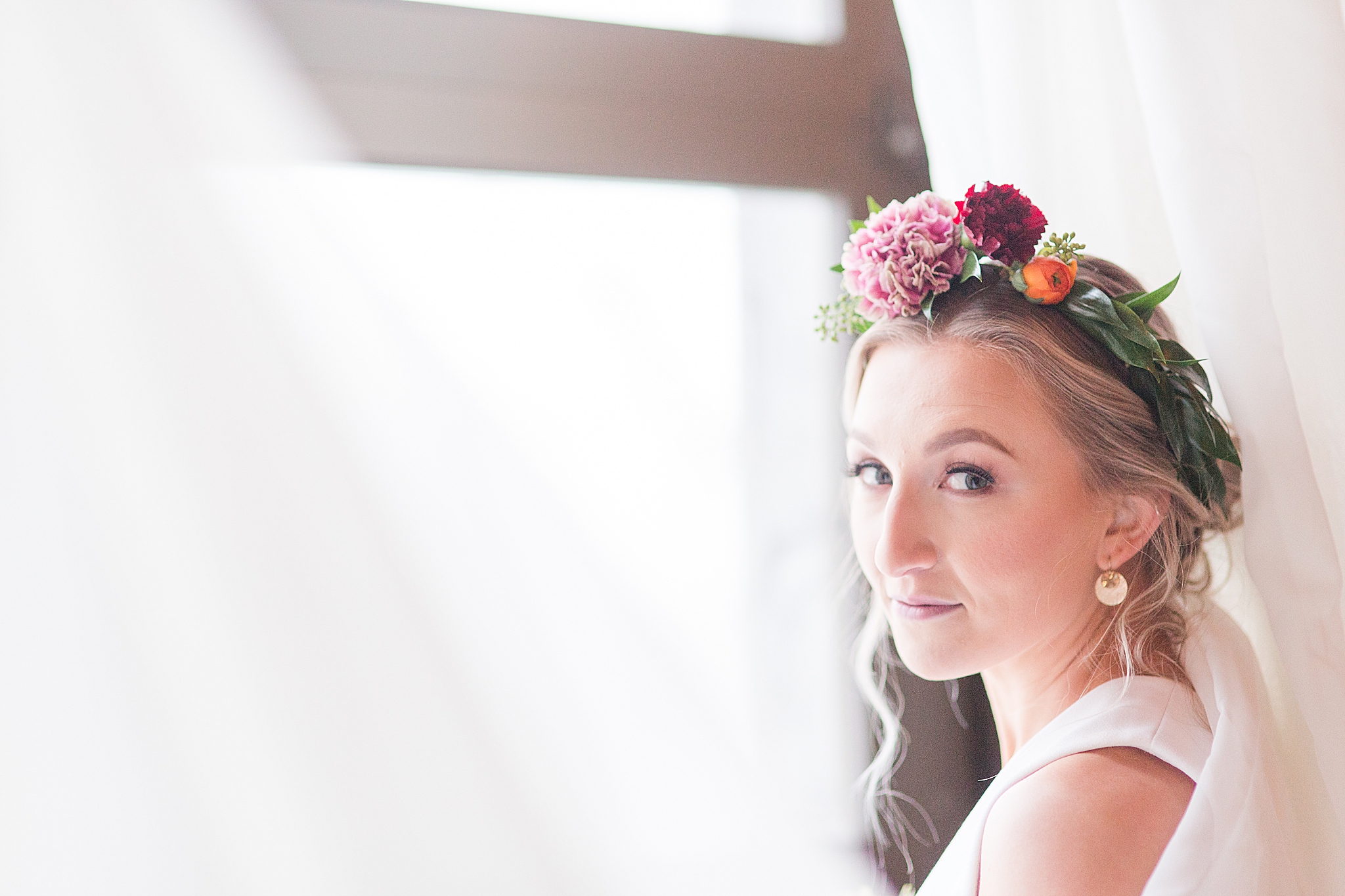 bride looks over shoulder wearing flower crown