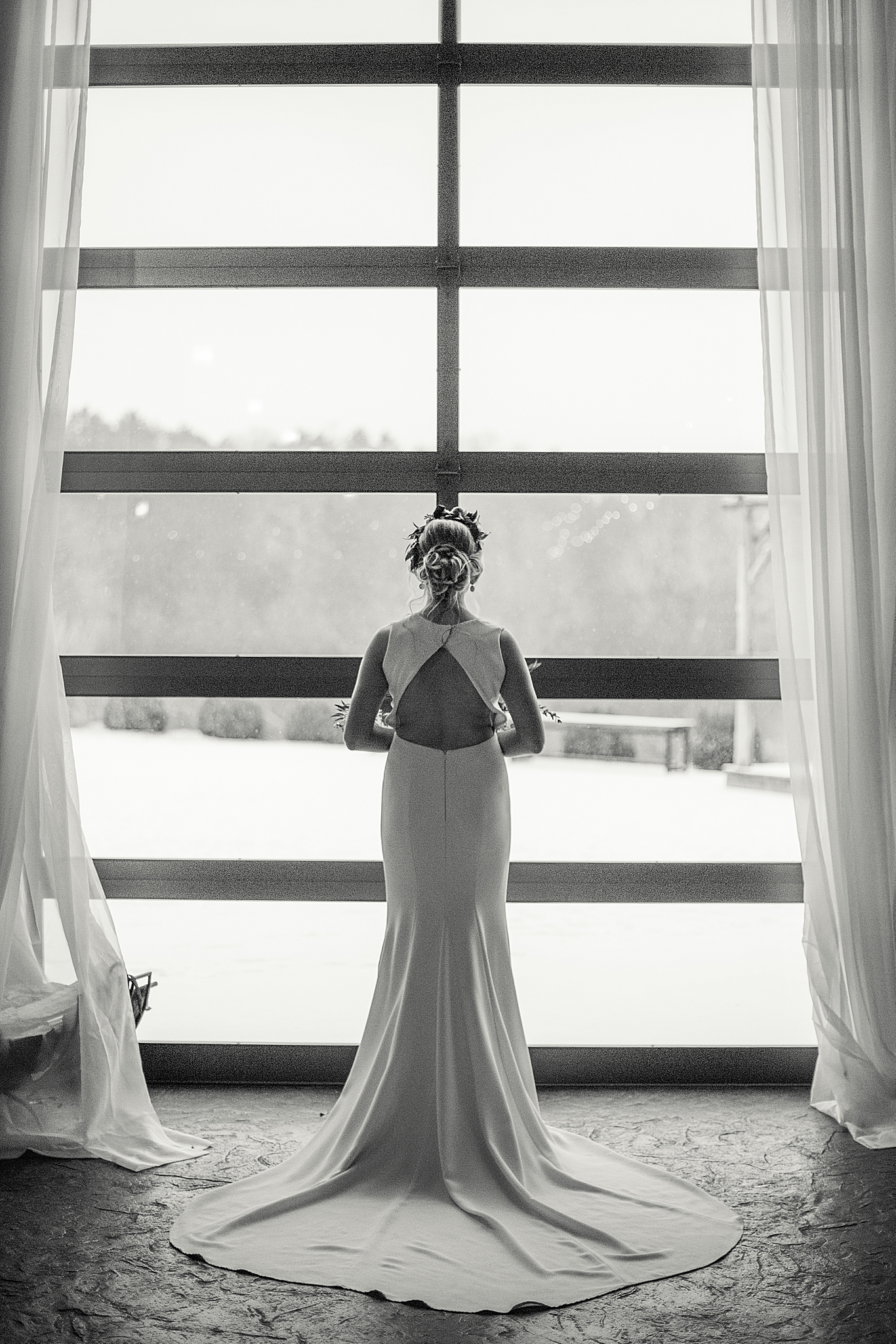 bride looks out window at snow during winter styled shoot in St. Louis MO