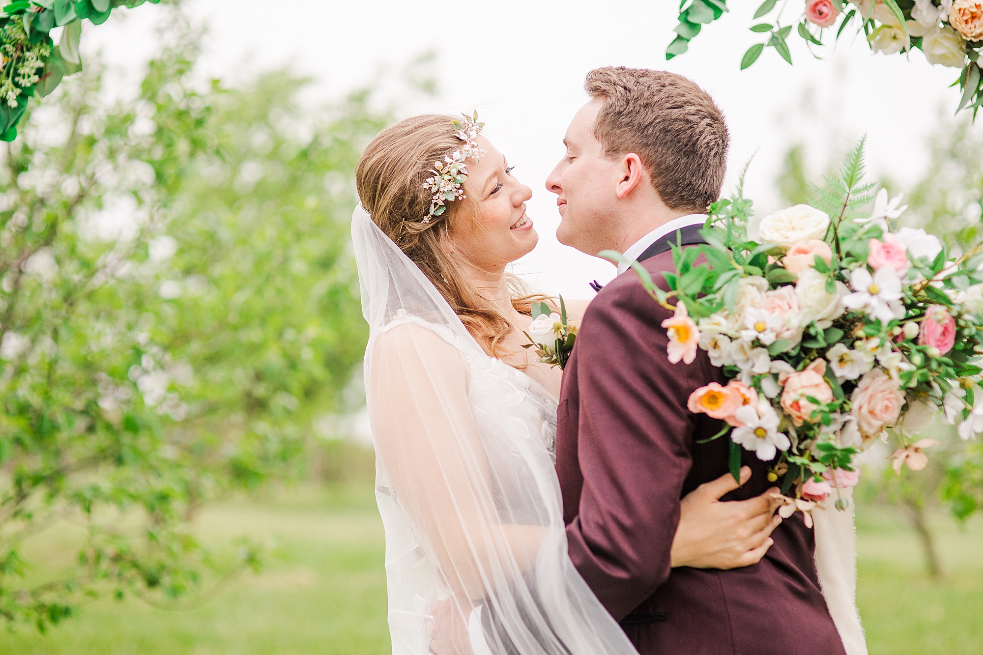 bride and groom smile by floral arbor at Pierce Century Farm