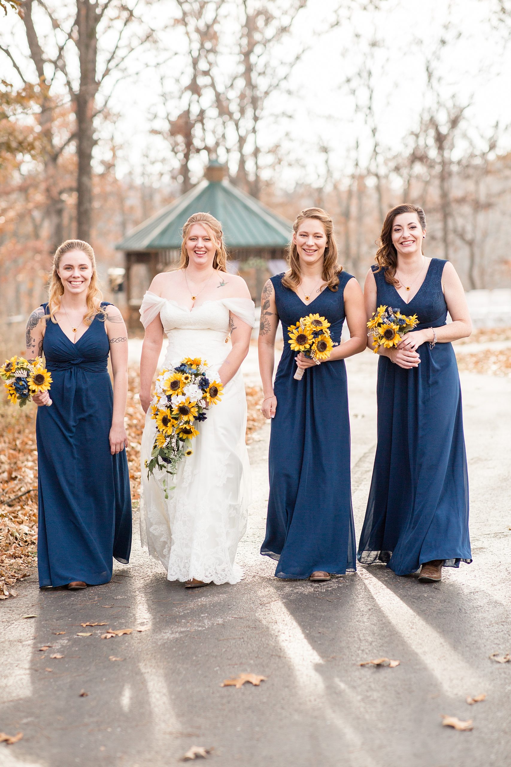 bride walks with bridesmaids in navy gowns for Quail Ridge Lodge wedding
