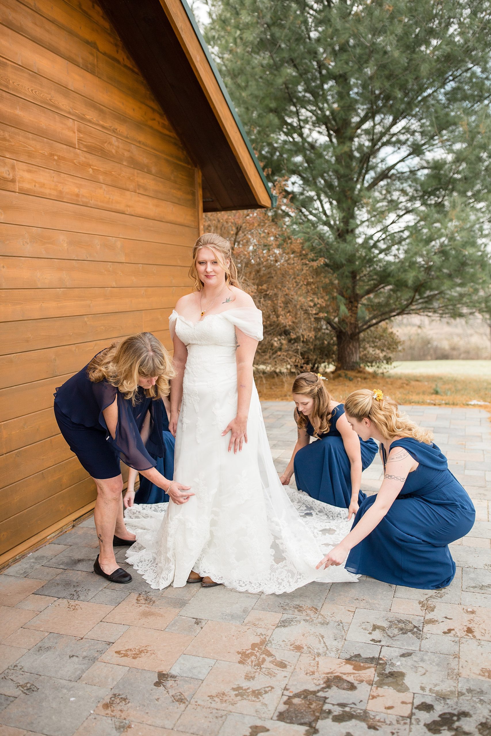 bridesmaids help bride adjust wedding gown
