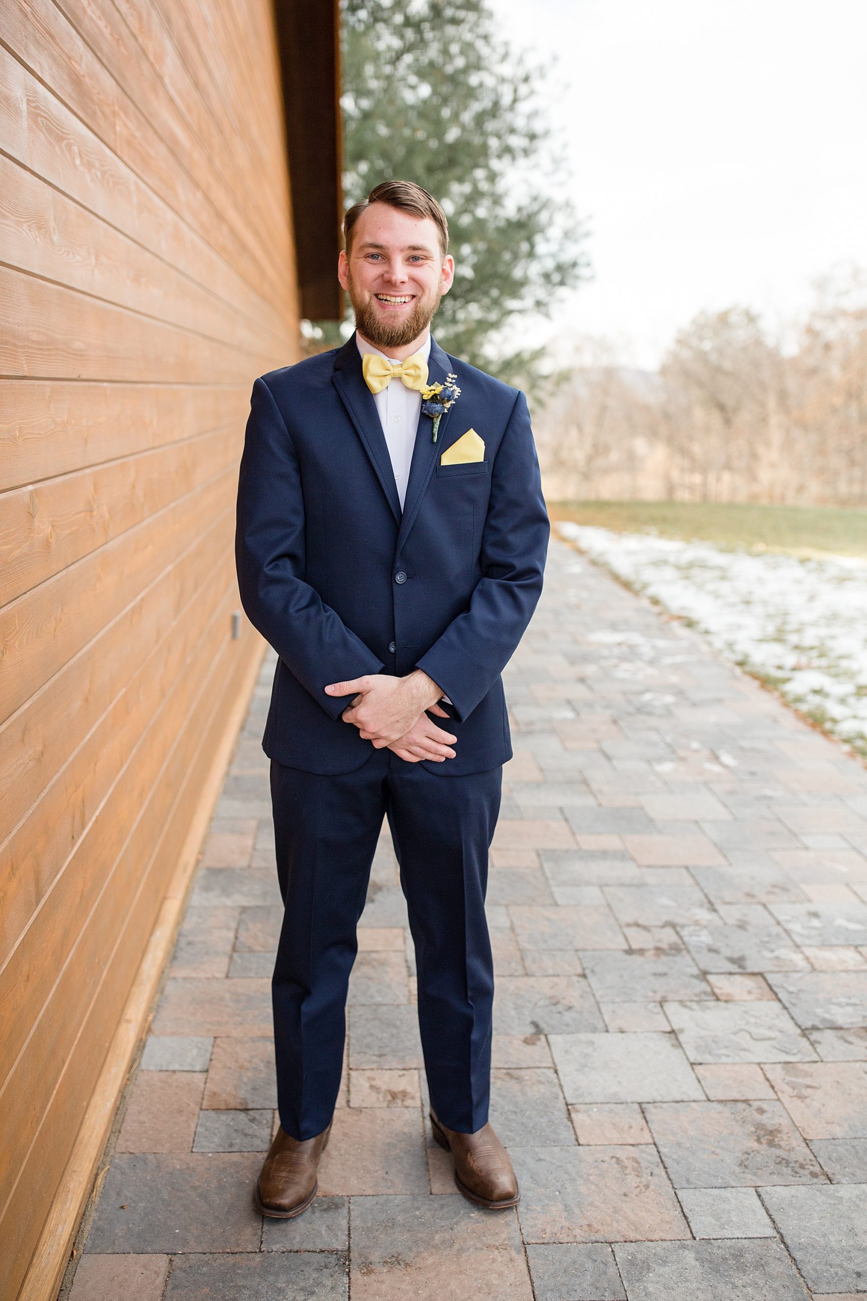 groom poses with hands in front of suit
