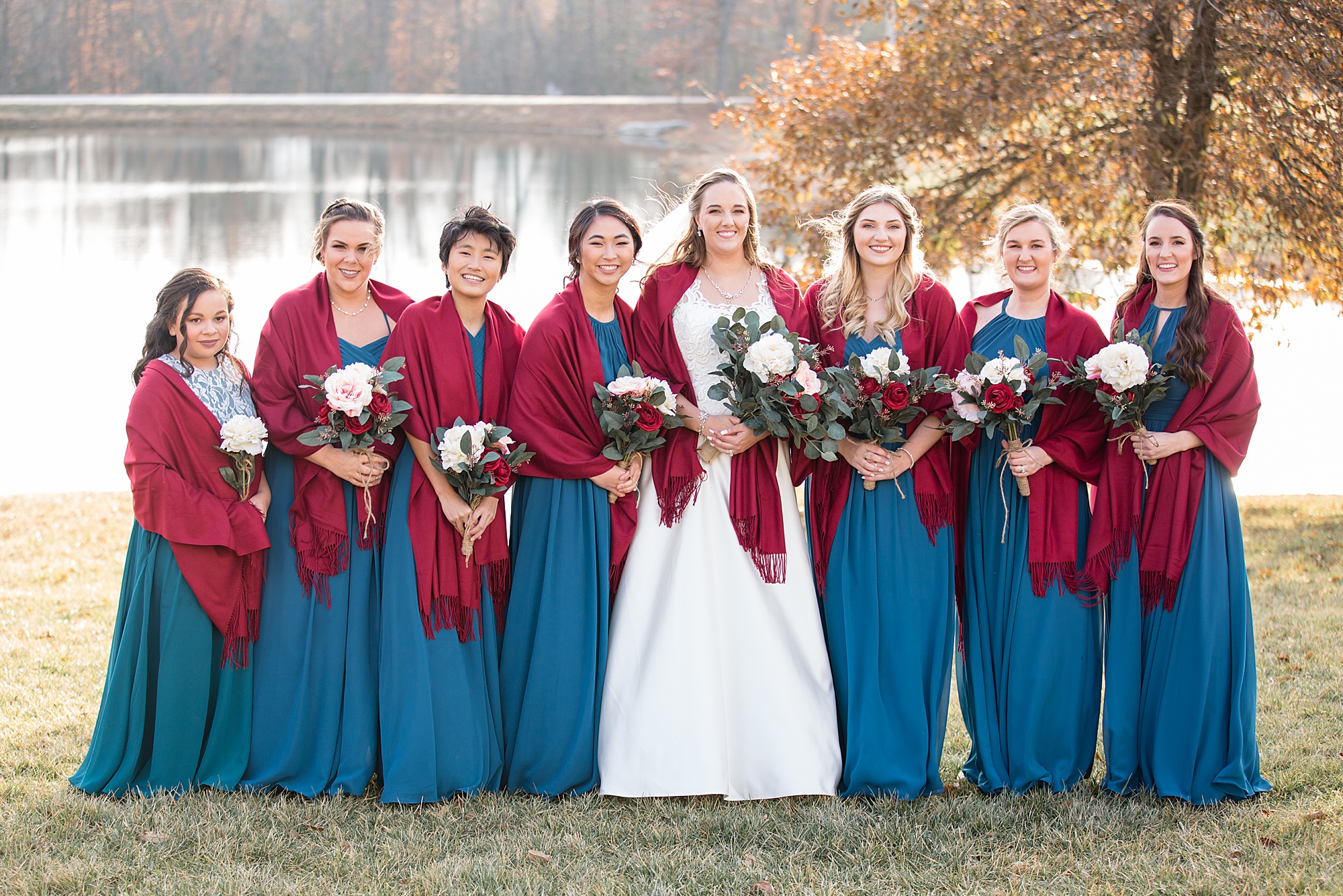 bride poses with bridesmaids in teal gowns