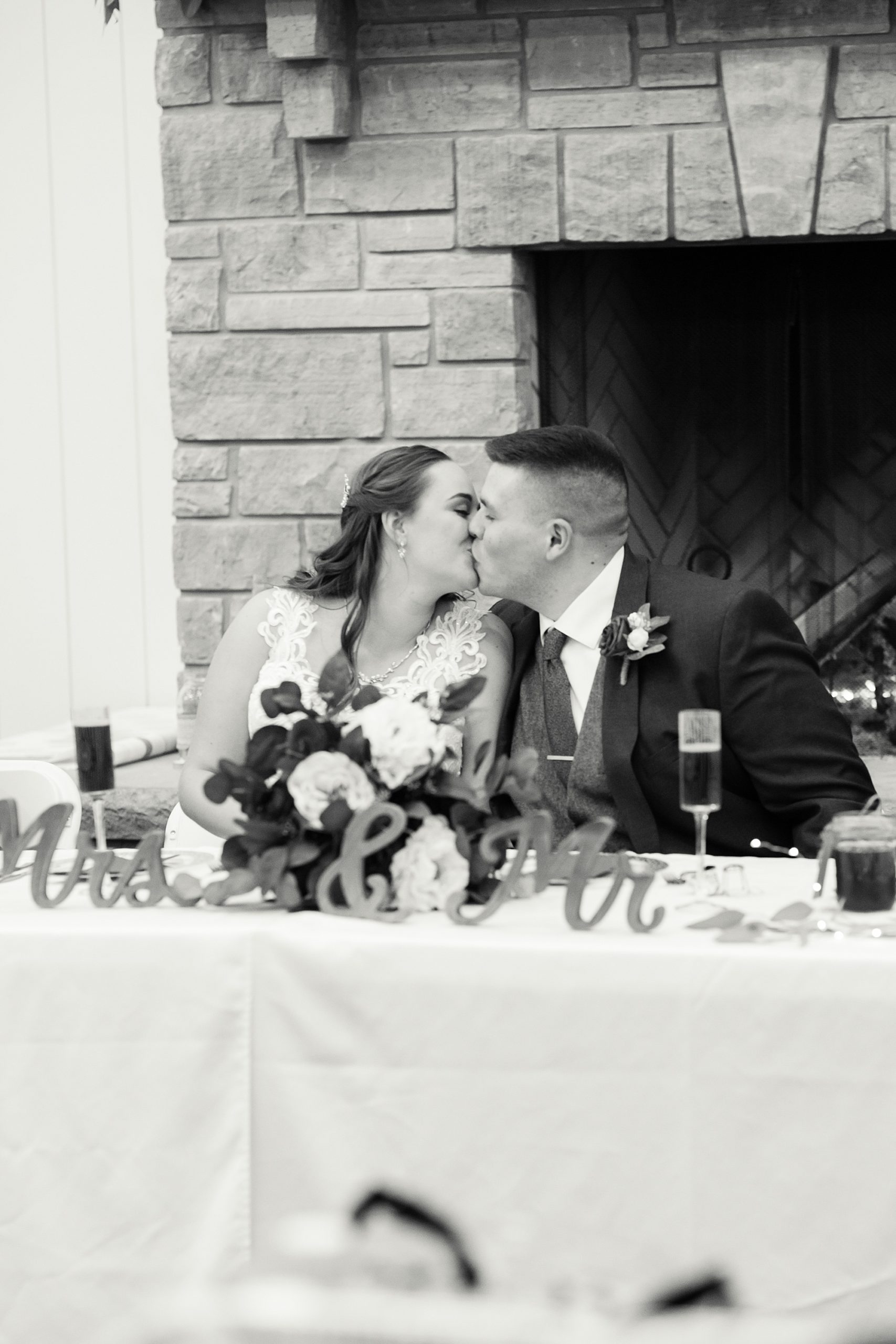 newlyweds kiss at sweetheart table at Redemption Ranch