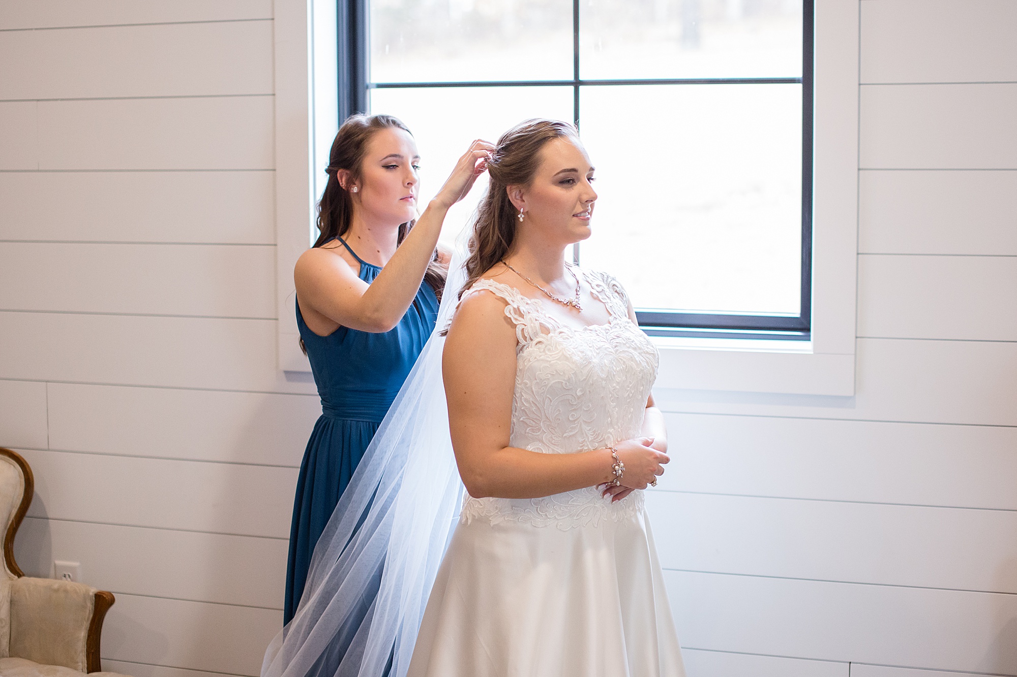 bridesmaid helps bride with veil before Redemption Ranch wedding