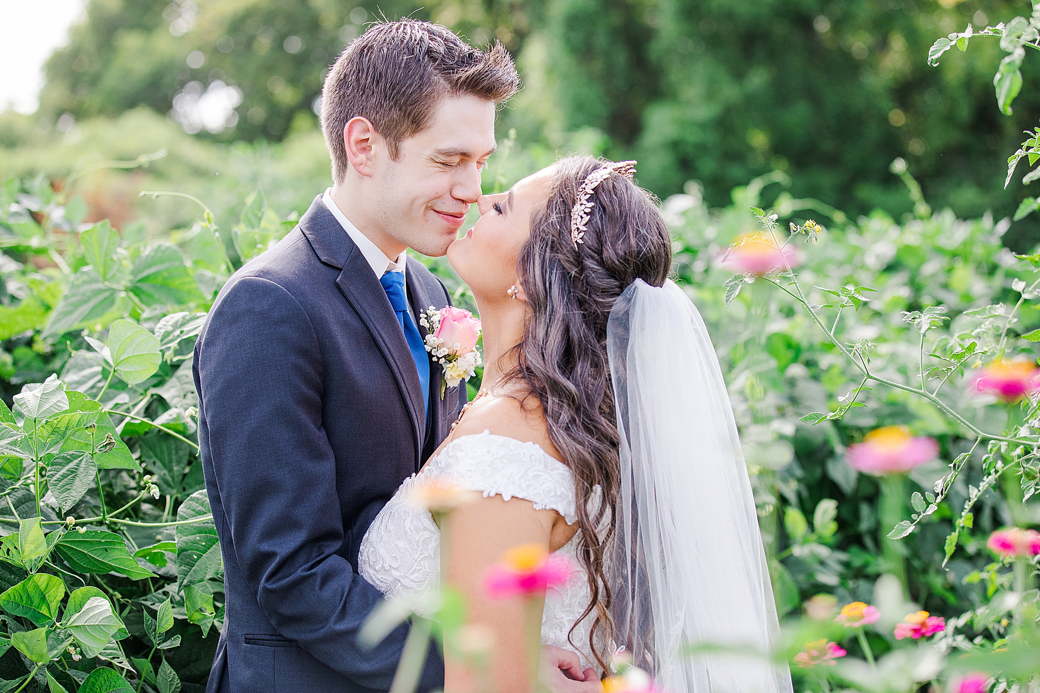 bride and groom kiss in gardens of Sacred Heart Catholic Church of Florissant