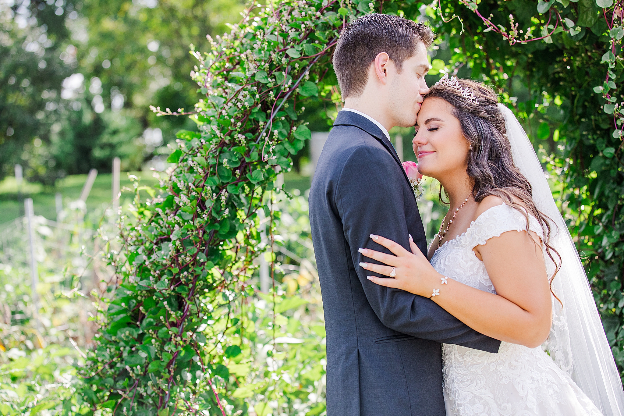 groom kisses bride by floral arbor at Sacred Heart Catholic Church of Florissant