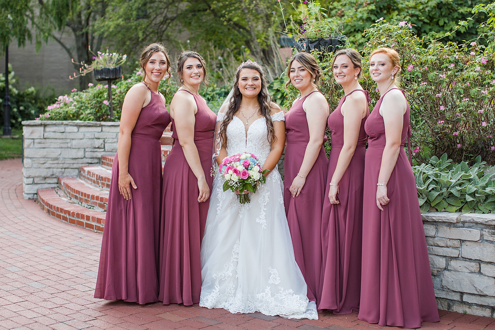 bride poses with bridesmaids in mulberry gowns