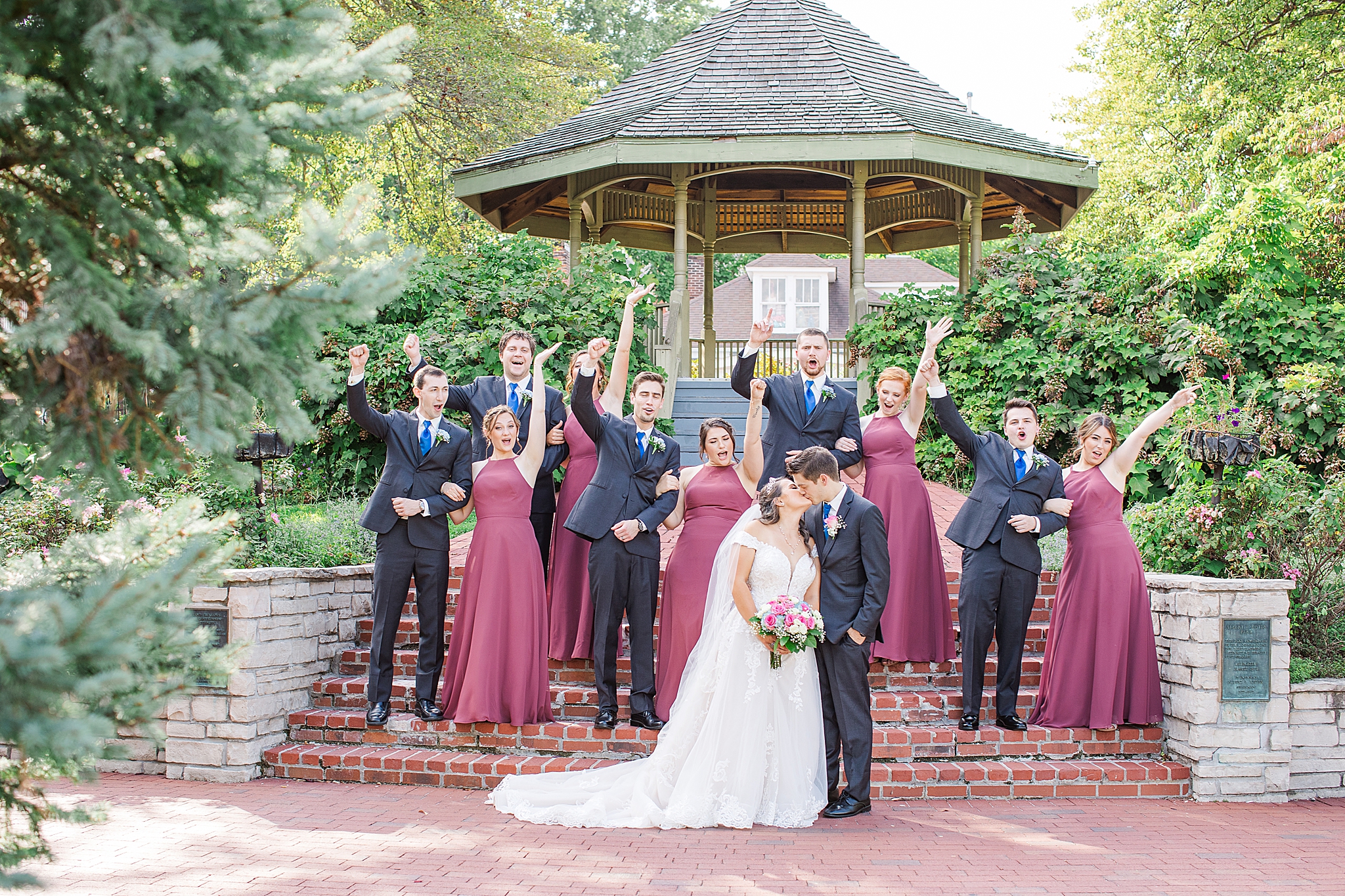 wedding party cheers while couple kisses
