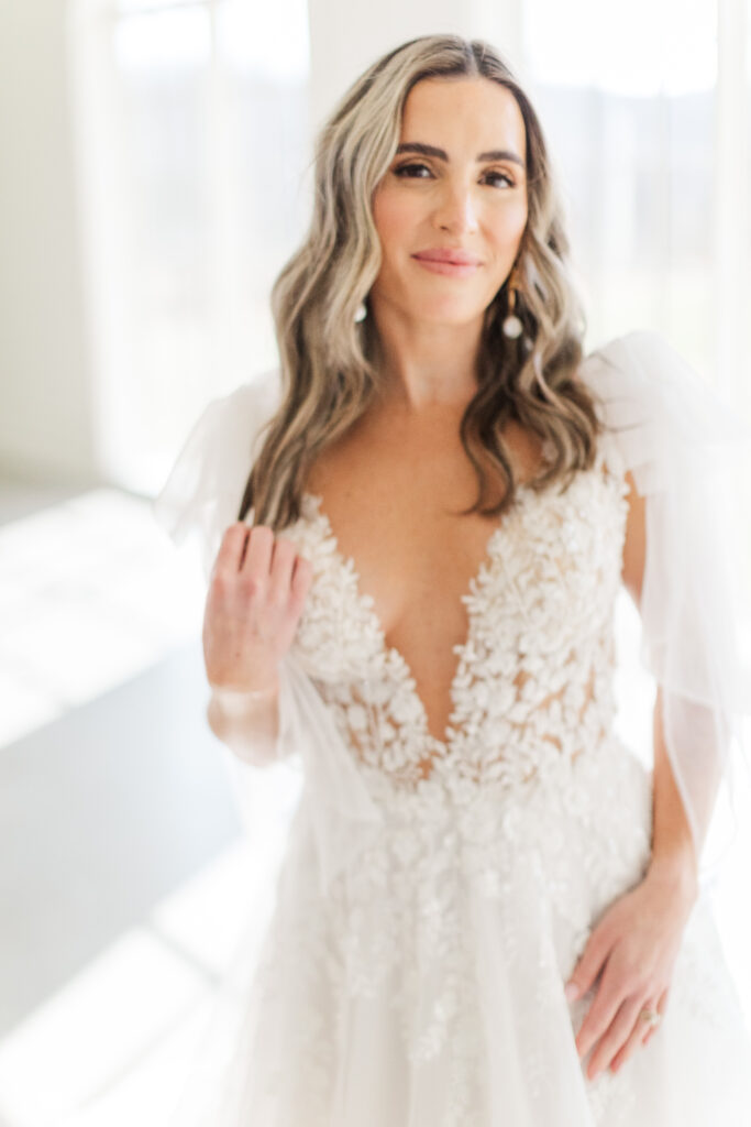 Elegant bridal close up portrait featuring a bride in a flowing lace and tulle gown, standing in the glowy sunlit ceremony space at Westwind Hills