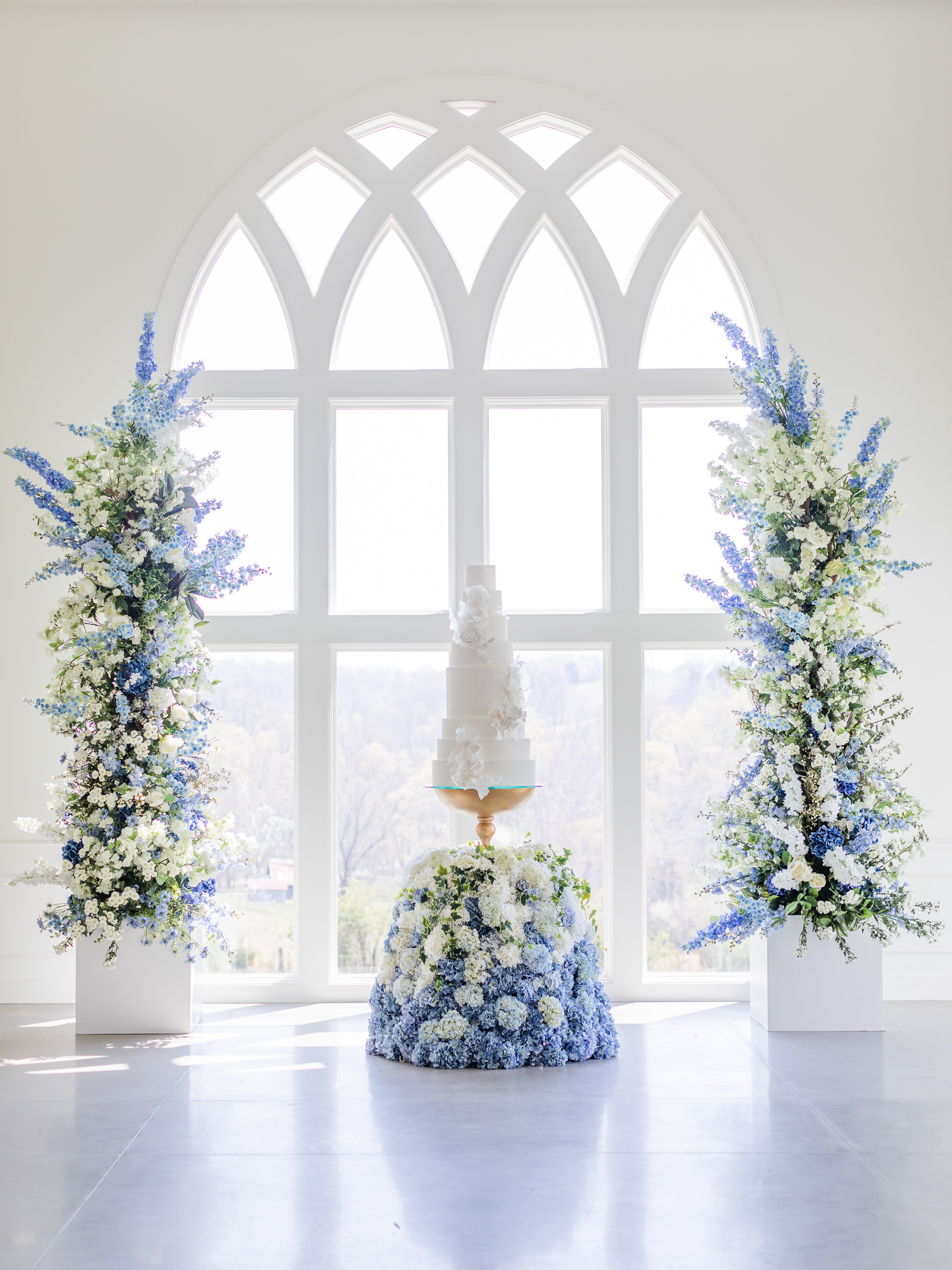 romantic wedding cake setup at Westwind Hills towering blue and purple floral cake display, and arched windows